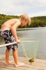 Boy looking at frog caught in net — Stock Photo