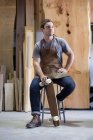 Carpenter at his workshop, holding skateboard — Stock Photo