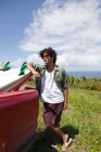 Young man leaning against surfboard in car, portrait — Stock Photo