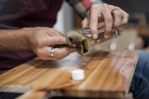 Primo piano dell'uomo che applica la macchia di legno al tagliere in fabbrica — Foto stock