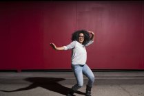 Retrato da mulher dançando na frente da parede vermelha — Fotografia de Stock