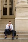 Businessman on steps using mobile phone — Stock Photo