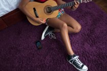 Hohe Winkel Brust nach unten Ansicht von Mädchen auf dem Boden sitzend Gitarre spielen — Stockfoto