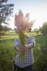 Retrato de jovem segurando um monte de snapdragons (antirrrhinum) do campo de fazenda de flores — Fotografia de Stock
