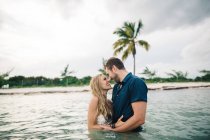 Couple waist deep in water face to face, smiling — Stock Photo