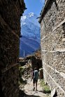 Woman treks through medieval stone buildings, Ghyaru, Nepal — Stock Photo