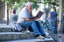 Кейптаун, Южная Африка, пожилой человек с ноутбуком сидит на ступеньках в городе — стоковое фото