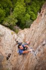 Rock climber scaling boulder crack — Stock Photo