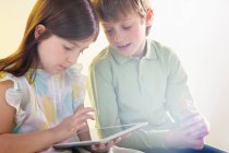 Chica y niño usando tableta digital con luz brillante - foto de stock