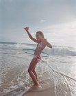 Fille hula cerclage dans vagues sur plage — Photo de stock