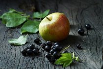 Manzanas y grosellas negras en la superficie de madera vieja - foto de stock