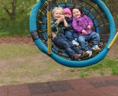Jeunes enfants sur l'aire de jeux balançoire, portrait — Photo de stock