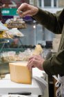 Cropped image of Cheesemonger cutting cheese — Stock Photo