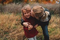Взрослая женщина целует дочь в щеку в поле — стоковое фото