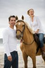 Мужчина и женщина с лошадью на пляже — стоковое фото