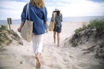 Женщины, гуляющие по песчаному пляжу, Амагансетт, Нью-Йорк, США — стоковое фото