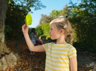Young girl looking at leaf in the garden — Stock Photo