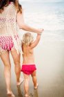 Visão traseira da mãe principal criança na praia — Fotografia de Stock