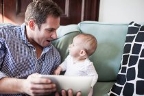 Pai usando tablet com bebê filha — Fotografia de Stock