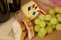 Pão, uvas e queijo com bandeiras na mesa — Fotografia de Stock