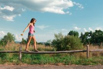 Девочка-подросток балансирует на деревянном заборе — стоковое фото