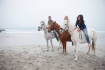 Persone a cavallo sulla spiaggia — Foto stock