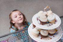 Girl admiring cupcakes in bakery — Stock Photo