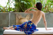 Visão traseira da mulher sentada na cama de massagem — Fotografia de Stock