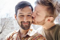 Retrato de casal masculino, homem adulto médio beijando a bochecha de seu parceiro — Fotografia de Stock
