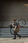 Männlicher Fahrradkurier trägt Fahrrad auf Gehweg — Stockfoto