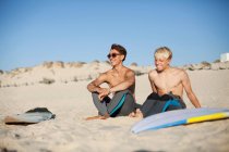 Dois jovens surfistas sentados numa praia — Fotografia de Stock