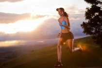 Young woman running in rural setting at sunrise — Stock Photo