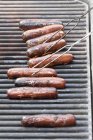 Row of sausages barbecuing on grill — Stock Photo