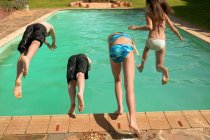 Niños saltando a la piscina - foto de stock