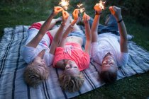 Young group of friends having fun with sparklers in park during summer — Stock Photo