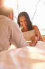 Young couple on bed reading newspaper — Stock Photo