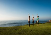 Women on cliff, in yoga positions — Stock Photo