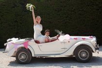 Молодожёны уезжают на медовый месяц на винтажном автомобиле — стоковое фото