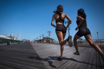 Women running together on wooden pier — Stock Photo