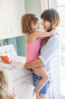 Mother and daughter hugging in utility room, portrait — Stock Photo