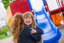 Mother catching daughter at the bottom of slide — Stock Photo