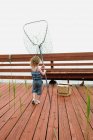 Mädchen läuft mit Netz auf Holzbrücke — Stockfoto