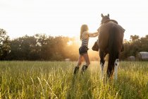Mulher andando cavalo no prado — Fotografia de Stock
