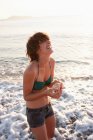 Femme tenant coquillages sur la plage — Photo de stock