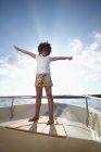 Young girl standing on motorboat with arms out — Stock Photo