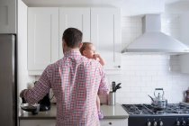 Mann hält Baby und kocht Tasse Kaffee — Stockfoto