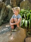 Больной мальчик, сидящий на камне — стоковое фото