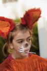 Little girl in fox costume sucking on lollipop — Stock Photo
