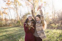 Dos mujeres divirtiéndose con hojas en el bosque - foto de stock