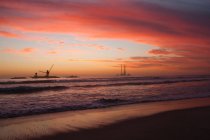 Закат над подводной лодкой на песчаном пляже — стоковое фото